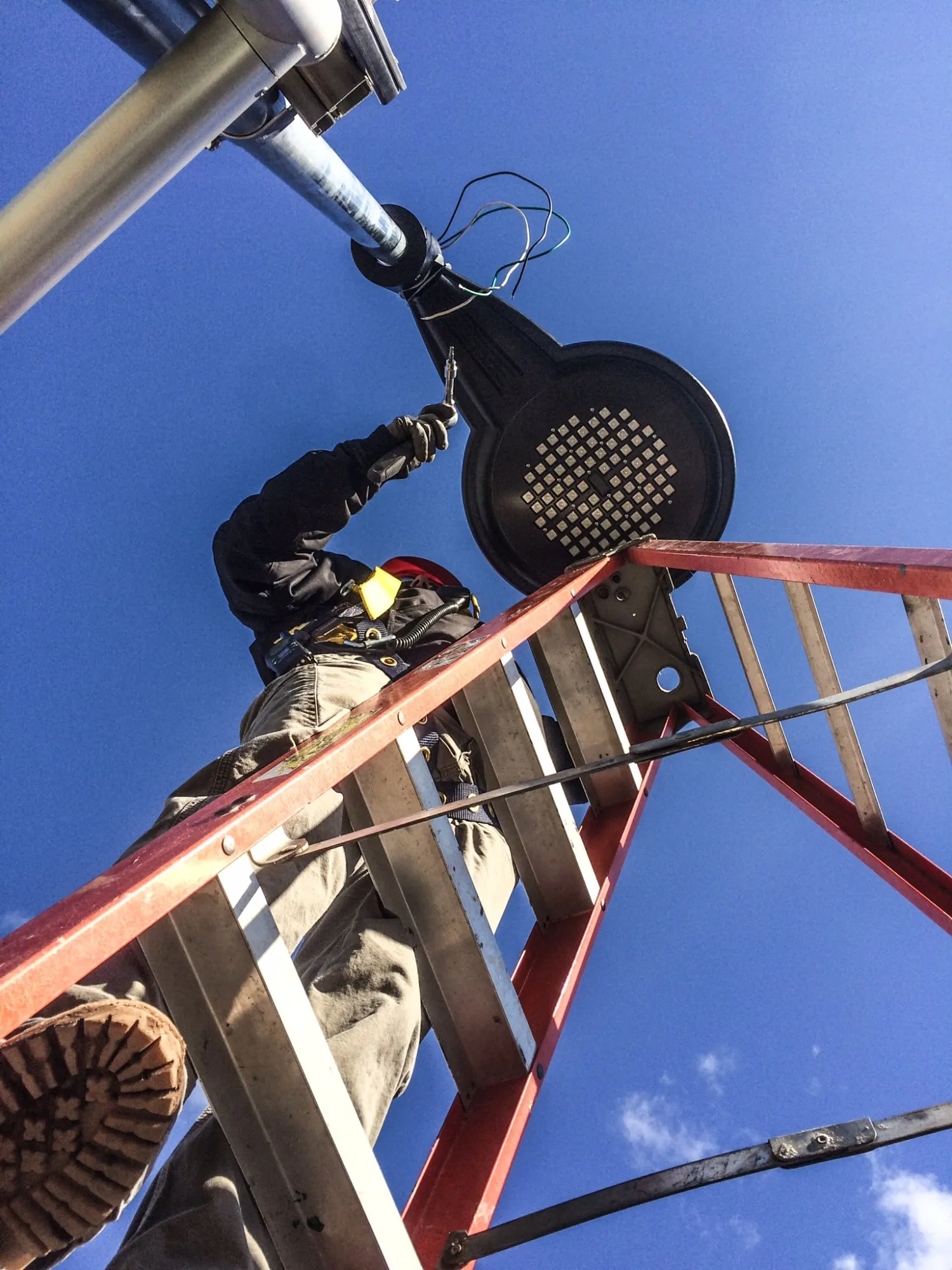 Martel Electric technician working on outdoor lighting from a ladder